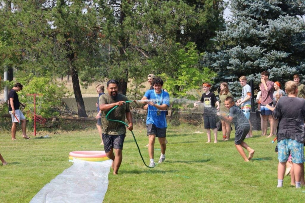 A leader and students in a water fight at camp