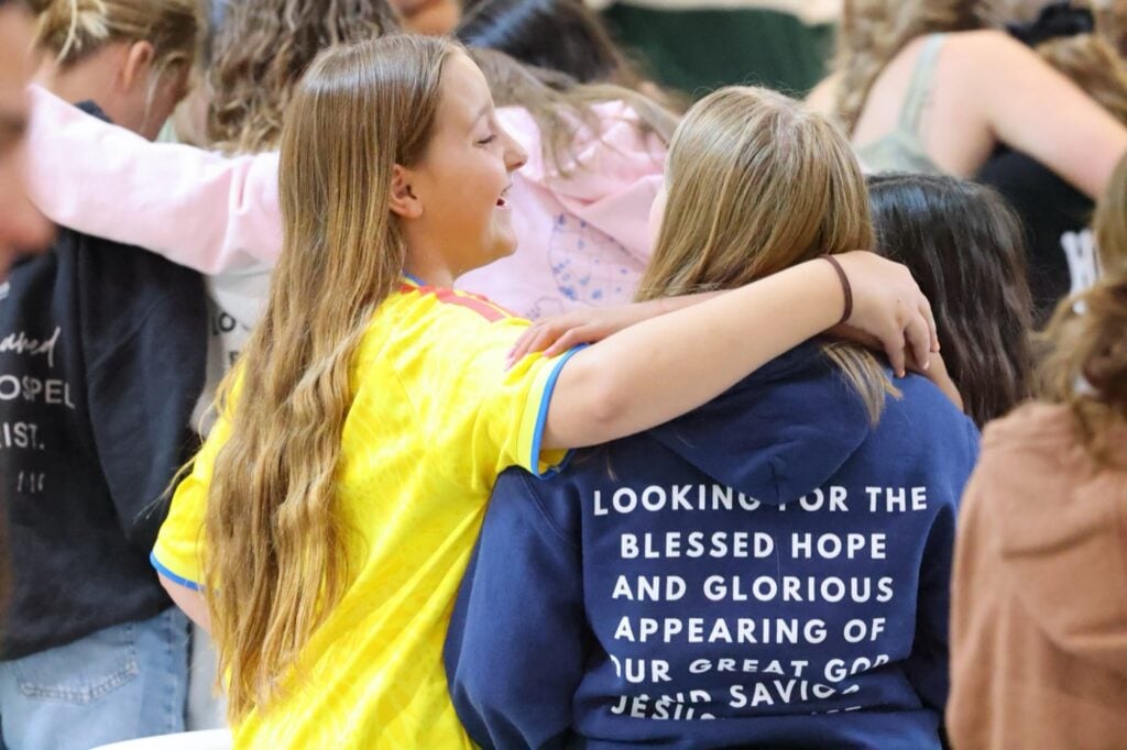 Two junior high girls laughing arm in arm