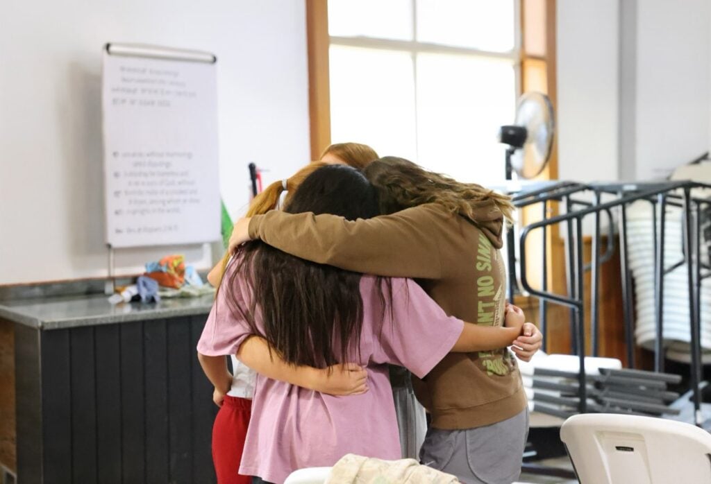 Junior high girls praying together in a huddle