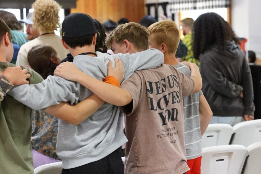 Junior high boys standing arm in arm during worship